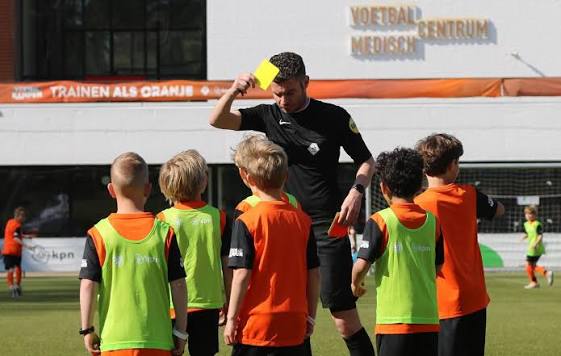 Trainer geeft uitleg aan jonge voetballers
